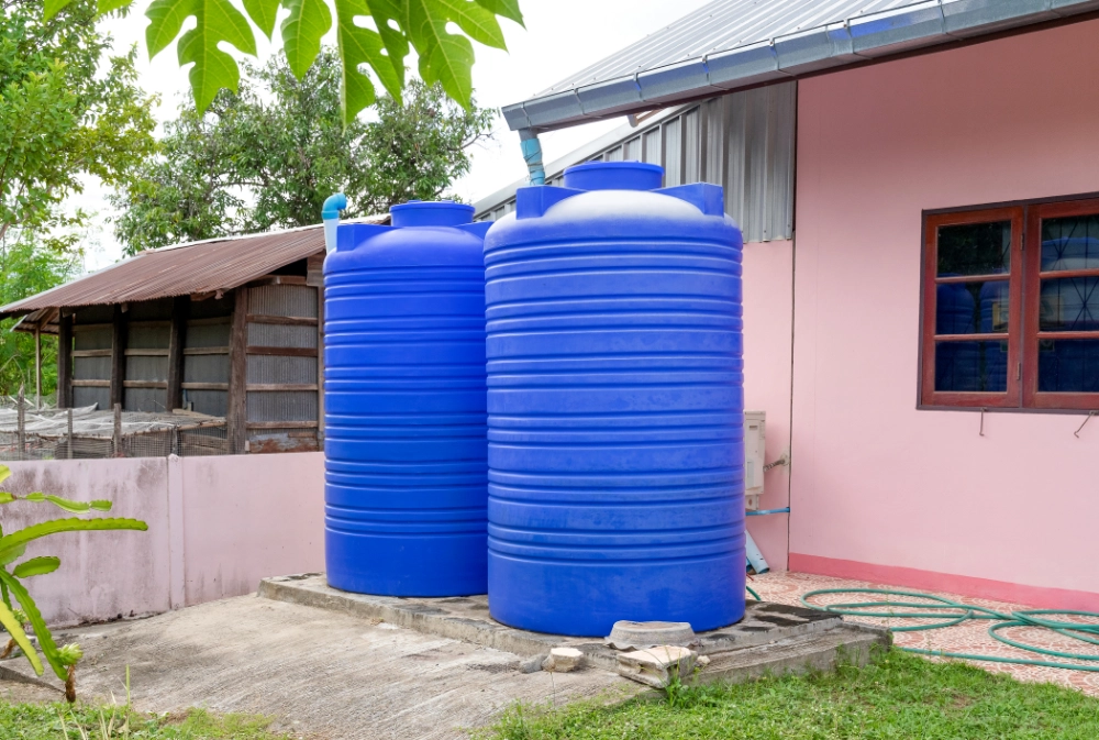 Two plastic water storage tanks in front of a residential property, supplied and installed by Deep End Plumbing.